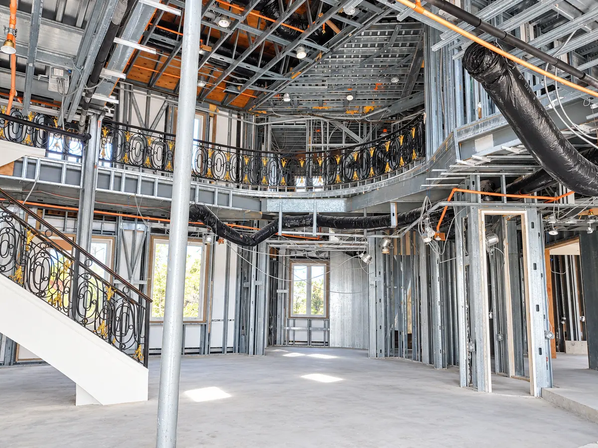 Two-story great room framed in cold-formed steel with a curved balcony and complex ceiling framing